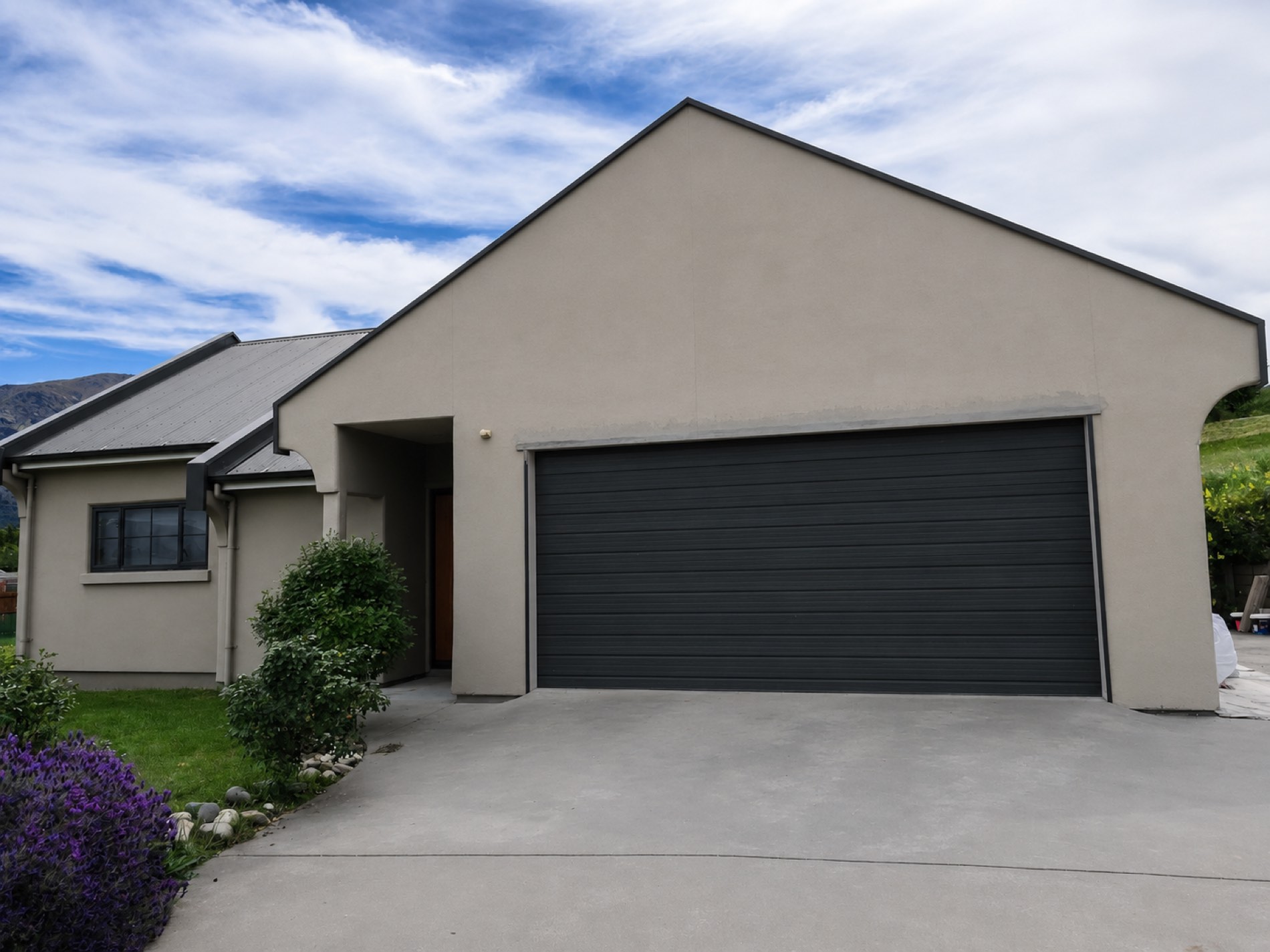 Repainted plaster home with fresh grey walls and a dark garage door
