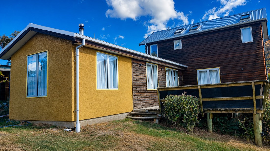 Refreshed textured cladding beside stained timber slats and a dark stained two storey home
