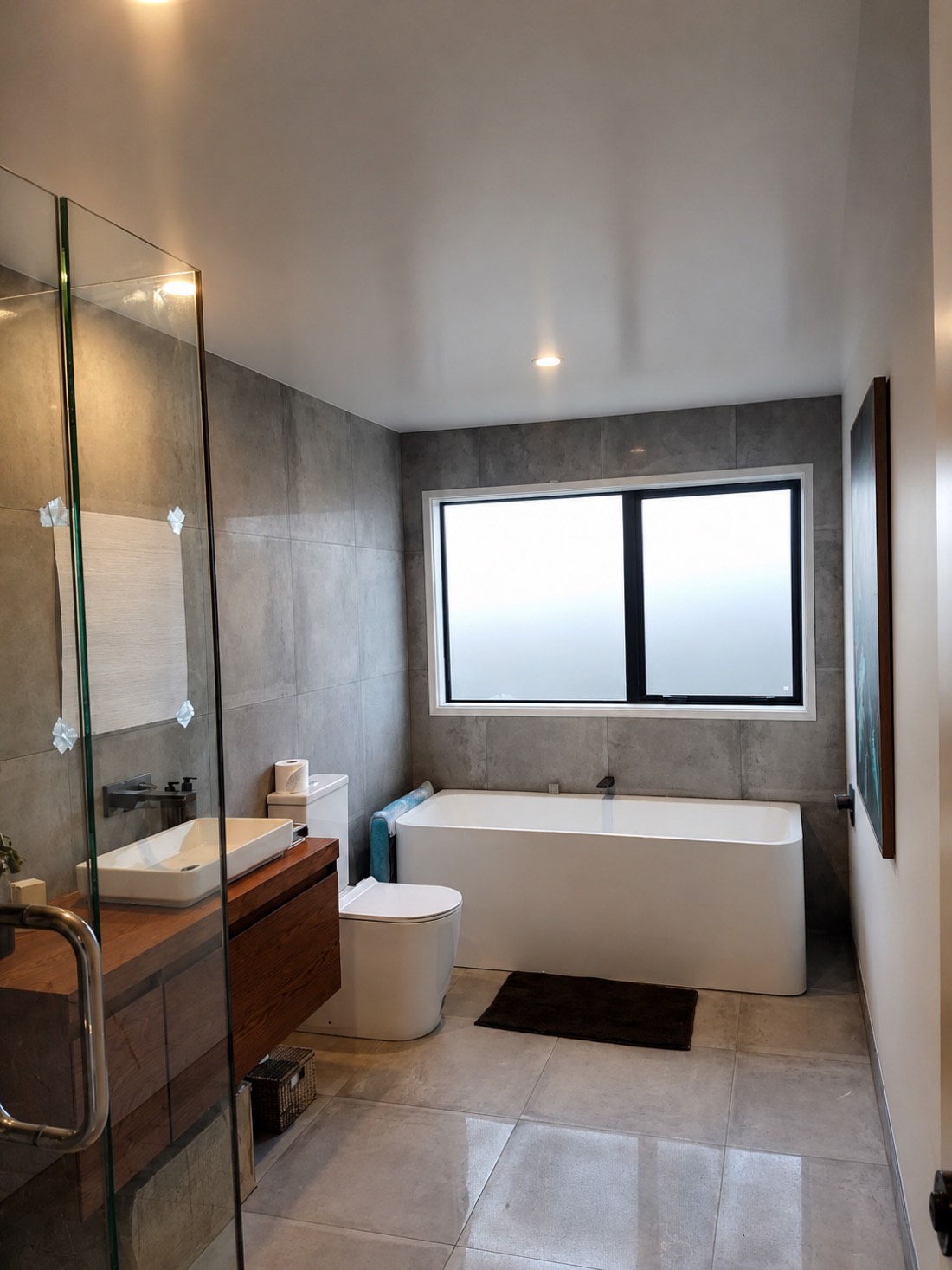 Finished bathroom with a clean white painted ceiling over grey tile